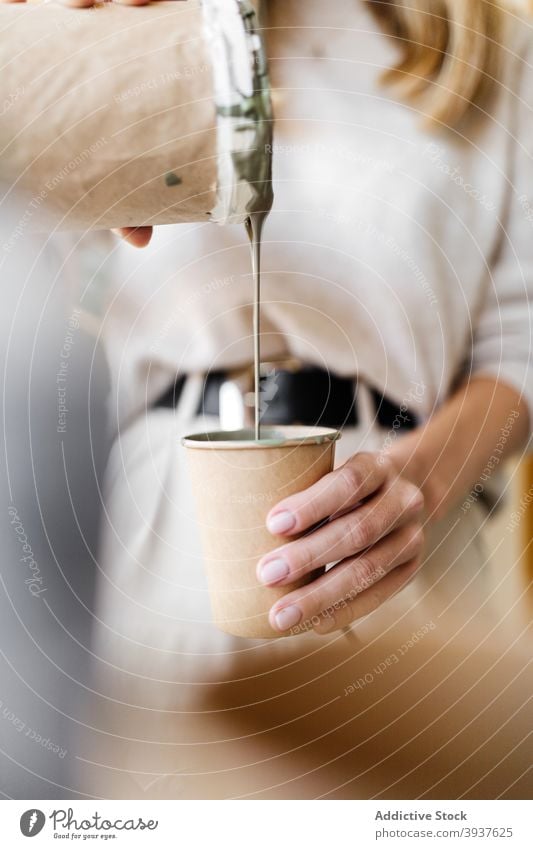 Frau mischen Farben für die Erstellung von Gemälde an der Wand Künstler Anstreicher heimwärts Pigment eingießen Fensterblätter Blatt Mundschutz behüten Tasse