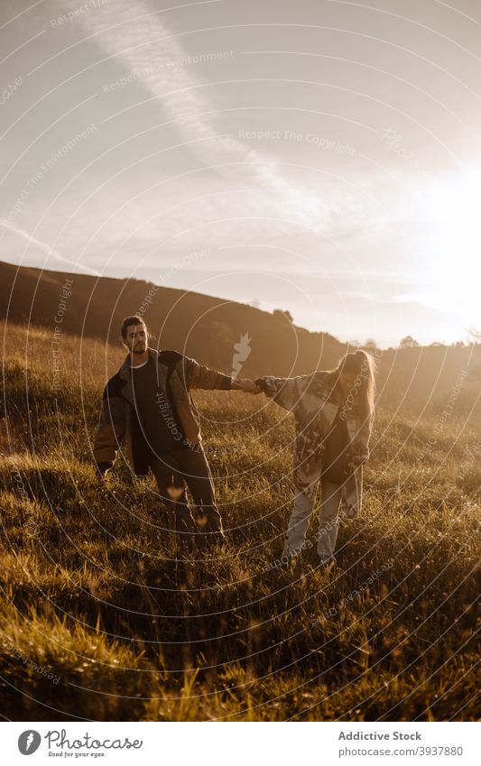 Paar steht zusammen im Feld bei Sonnenuntergang Händchenhalten Zusammensein Liebe retro Outfit Stil altehrwürdig Zuneigung Abend Glück Partnerschaft jung