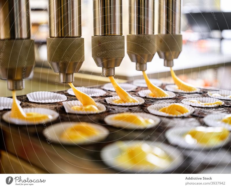 Muffin-Zubereitung mit Automat Teigwaren besetzen Maschine automatisch industriell Gerät Inszenierung professionell Bäckerei vorbereiten Gebäck Lebensmittel