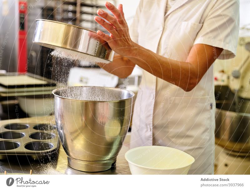 Bäcker siebt Mehl in eine Schüssel in der Küche Gebäck Konditorei Küchenchef sieben Sieb vorbereiten professionell Teigwaren Bäckerei kulinarisch Koch