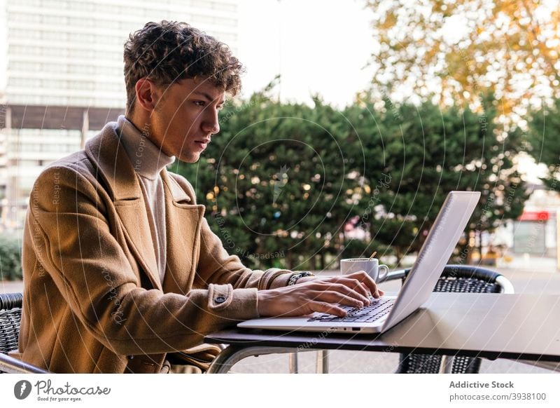 Ernster Mann arbeitet am Laptop im Straßencafé freiberuflich Tippen abgelegen Café Arbeit Projekt Browsen Großstadt männlich ernst Fokus Konzentration Gerät