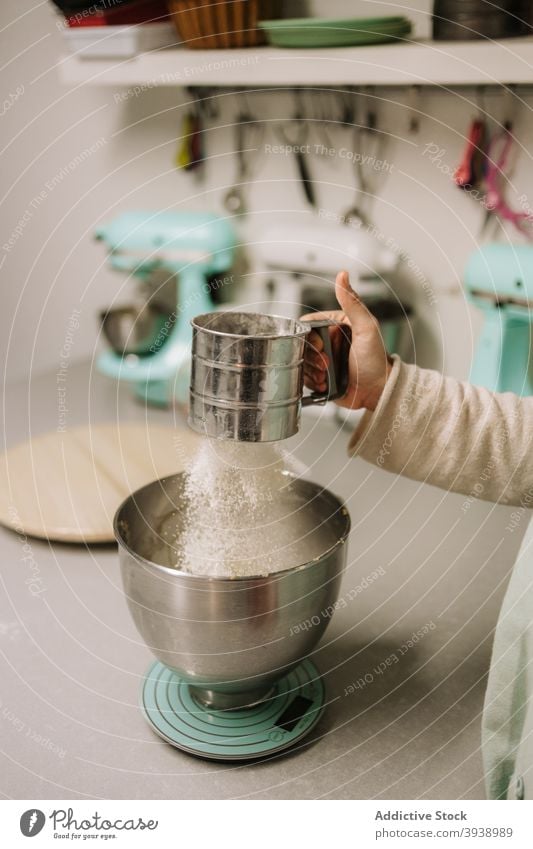 Anonyme Frau, die Mehl in eine Schüssel gibt Konditorei Sieb Schalen & Schüsseln vorbereiten Gebäck Bäckerei Dessert Lebensmittel Küche Bestandteil kulinarisch