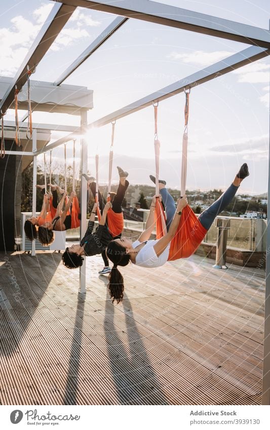 Frauen machen Yoga in Hängematten auf der Terrasse Klasse Menschengruppe üben hängen Asana Pose beweglich Sportkleidung sonnig Zusammensein Gesundheit