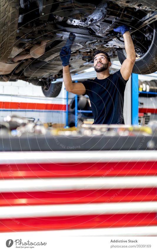 Techniker überprüft Auto im modernen Service untersuchen PKW Mechaniker Mann Dienst Taschenlampe Fackel Automobil Fahrzeug Reparatur Beruf männlich Verkehr