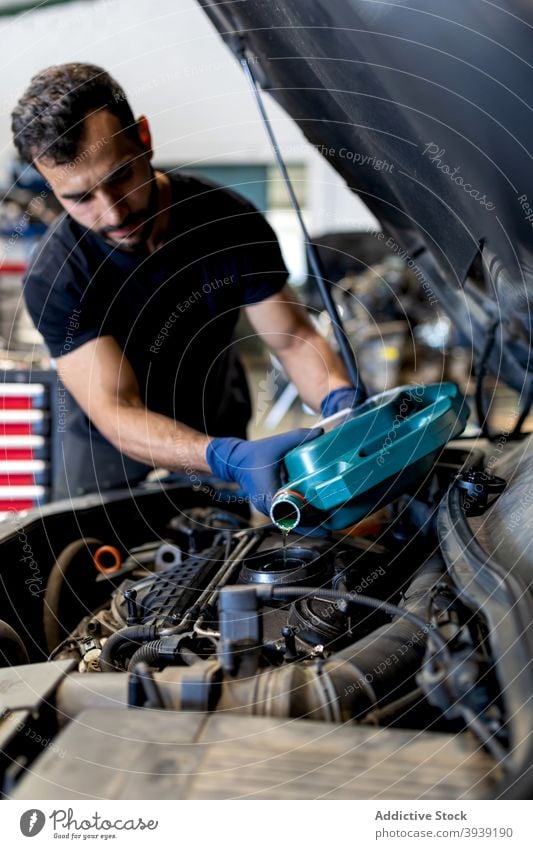 Männlicher Techniker beim Motorölwechsel im Autoservice Mann Wandel & Veränderung Erdöl PKW eingießen Dienst Flugzeugwartung männlich Mechaniker ernst Garage