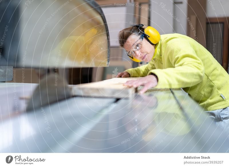 Seriöse Handwerkerin bei der Arbeit an der Tischsäge Frau Säge Holz Maschine Kunstgewerbler Hobelbank Fokus Tischlerarbeit Werkstatt Beruf hölzern Holzplatte