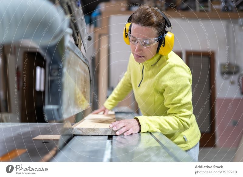 Seriöse Handwerkerin bei der Arbeit an der Tischsäge Frau Säge Holz Maschine Kunstgewerbler Hobelbank Fokus Tischlerarbeit Werkstatt Beruf hölzern Holzplatte