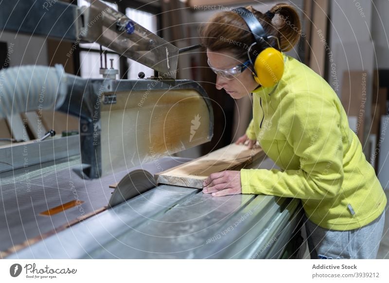 Seriöse Handwerkerin bei der Arbeit an der Tischsäge Frau Säge Holz Maschine Kunstgewerbler Hobelbank Fokus Tischlerarbeit Werkstatt Beruf hölzern Holzplatte