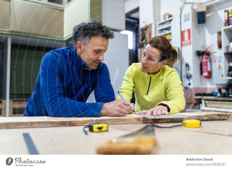 Fokussierte Kollegen messen Holz in moderner Werkstatt Holzarbeiten Zusammensein Konzentration Meister Tischlerarbeit Beruf professionell Mitarbeiterin Mann