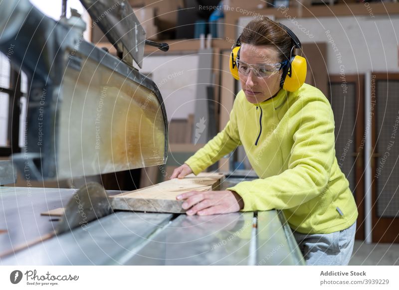 Seriöse Handwerkerin bei der Arbeit an der Tischsäge Frau Säge Holz Maschine Kunstgewerbler Hobelbank Fokus Tischlerarbeit Werkstatt Beruf hölzern Holzplatte