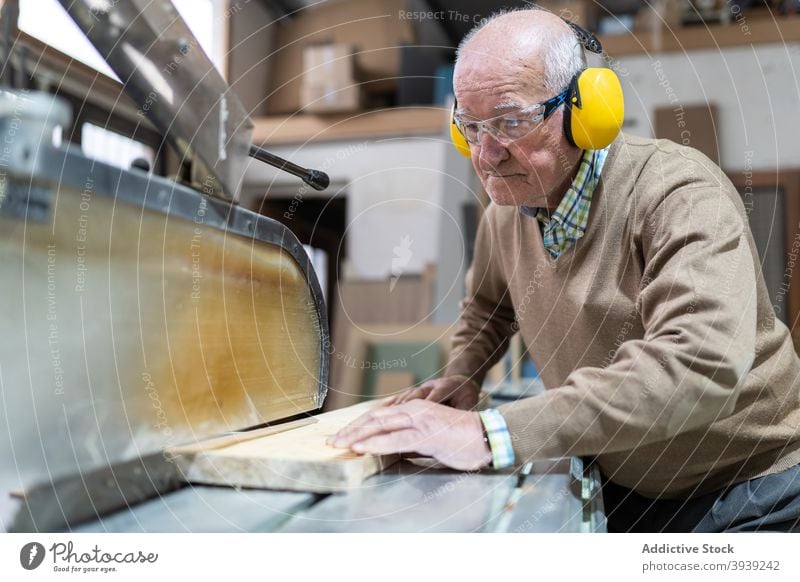 Seriöser Handwerker bei der Arbeit an der Sägetischmaschine Holz Maschine Kunstgewerbler Hobelbank Fokus Tischlerarbeit Werkstatt Beruf hölzern Holzplatte