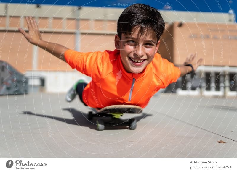 Glücklich ethnischen männlichen Teenager auf Skateboard liegen und lächelnd Junge Lügen Mitfahrgelegenheit Gleichgewicht Spaß Aktivität Hobby heiter dynamisch