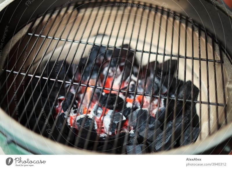 Glühende Holzkohle in einem Keramikgrill unter dem Grillgitter kurz nach Entzündung Grillrost Holzkohle Glut Kamado Kamadogrill Grün Großes Grünes Ei heiß Ruß