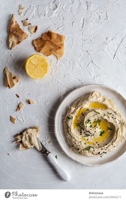 Draufsicht auf einen Teller mit Hummus mit libanesischem Fladenbrot und Zitrone auf weißem Hintergrund Amuse-Gueule arabisch arabische Küche Brot Kichererbsen