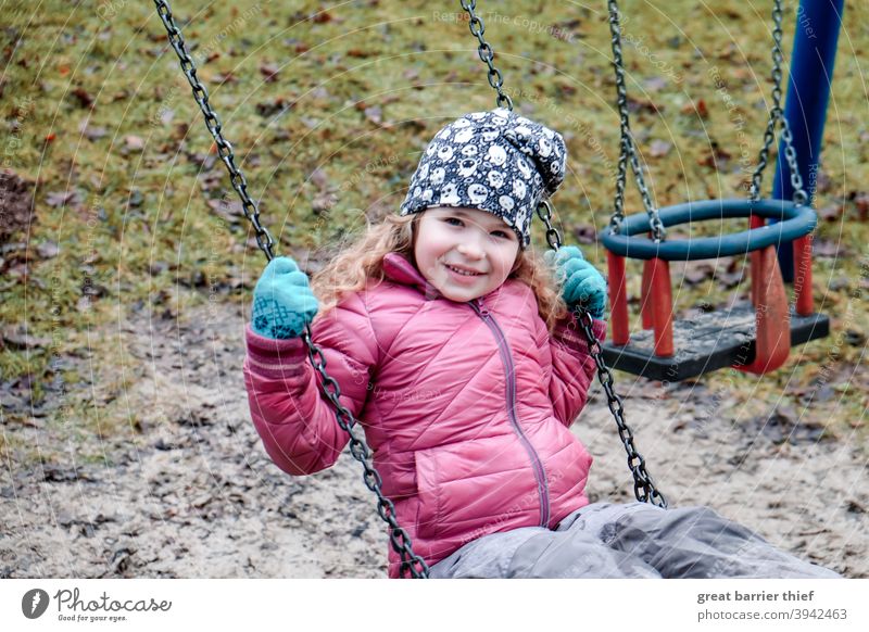 Mädchen auf der Schaukel Winter Spielplatz schaukeln Spielen Kind Kindheit fröhliches Kind Freude rote jacke lachen lachendes kind 3-8 Jahre Kindergartenkind