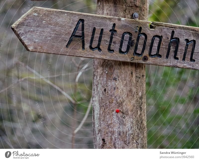 Autobahnschild aus Holz im Wald Richtung fahren Schilder & Markierungen Holzschild Verkehr Geschwindigkeit Verkehrswege Autofahren Außenaufnahme Farbfoto PKW