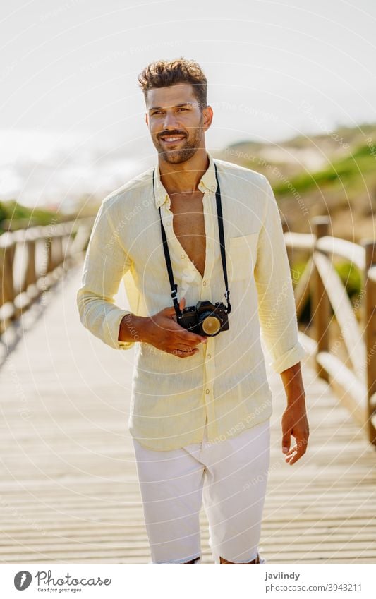 Lächelnder Mann beim Fotografieren in einer Küstengegend. Fotokamera Reisender Tourist Strand Sommer Natur Tourismus reisen Urlaub zahnfarben Feiertag Hobby