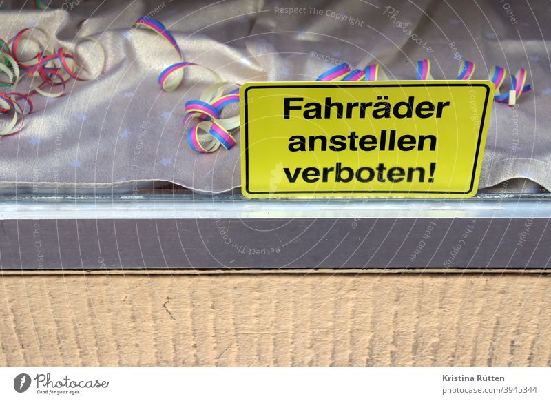 fahrräder anstellen verboten schild im schaufenster mit luftschlangen deko abstellen verbotsschild hinweis hinweisschild laden geschäft dekoration partydeko