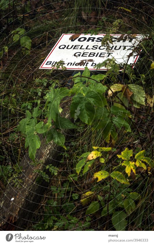 systemrelevant | Trinkwasser. Quellschutzgebiet, geschützt durch eine Warntafel, die aber am Boden liegt. Hinweisschild Verbotsschild Einschränkung