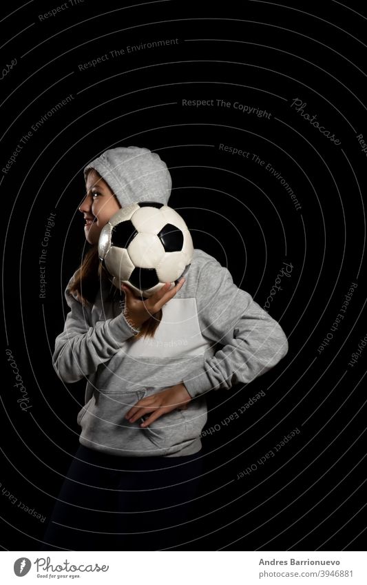 Kleines Mädchen in grauem Sweatshirt und zwei Zöpfen spielen mit einem Fußball isoliert auf schwarzem Hintergrund Sport Auge vereinzelt geschnitten Lifestyle