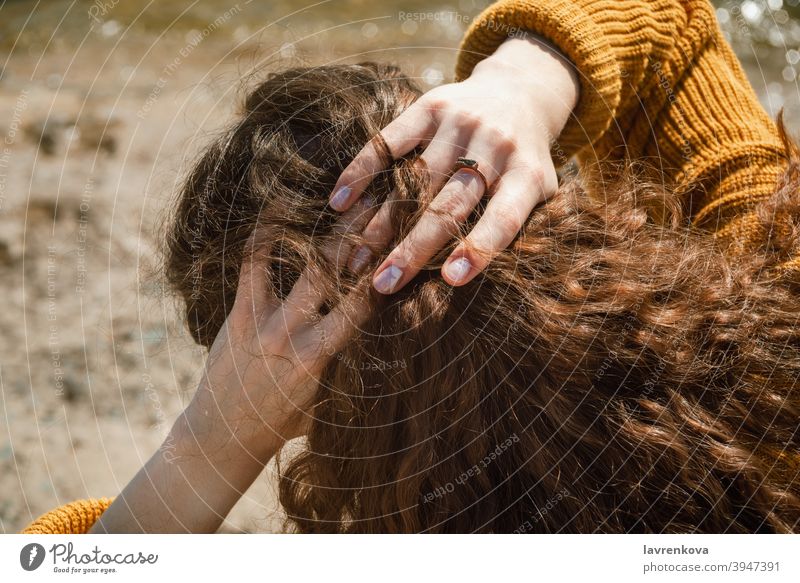 Draufsicht auf weibliche Hände, die dunkle lockige Haare hinter ihrem Kopf im Freien halten Frau brünett Mädchen Lifestyle Erwachsener Finger Flechten jung