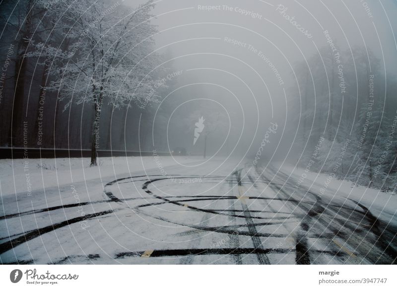 Reifenspuren auf einer glatten Straße mit Schnee und Eis Bäume Wald Weg Winter Auto Scheinwerferlicht Spuren glatteis asfalt asfaltstraße Menschenleer kalt PKW