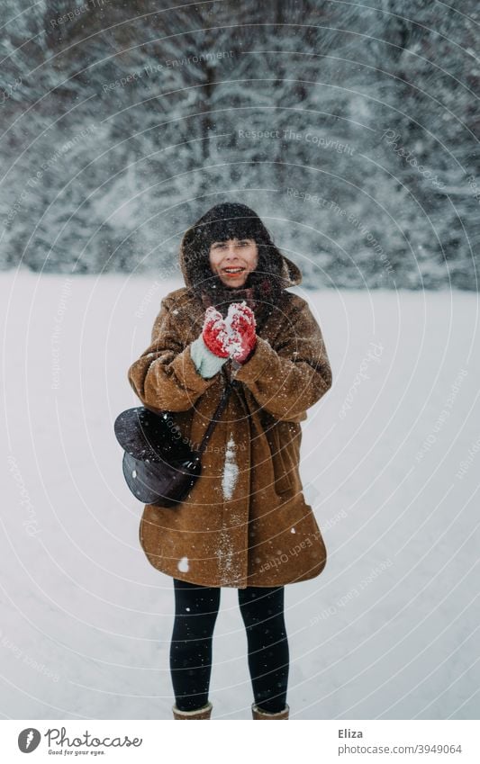 Eine Frau im Schnee Schneeball Winter lustig Freude dunkelhaarig Mensch weiß Winterlandschaft Landschaft draußen Natur schneien Schneefall Wintertag winterlich