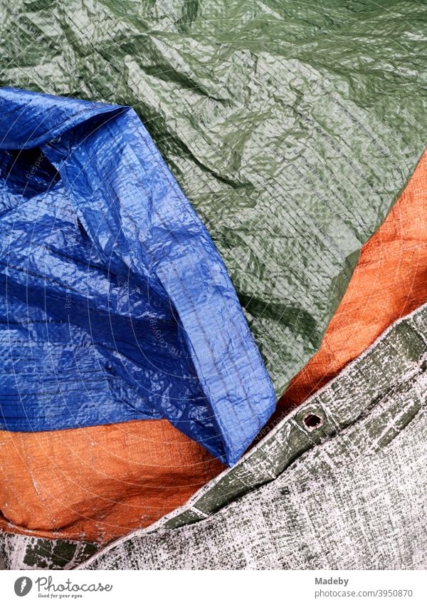 Wasserfeste Plane mit Struktur und Ösen zum Abdecken bei Regen in Grün, Blau und Orange Schutzplane Regenschutz Wasserdicht Abdeckplane Stilleben Hintergrund