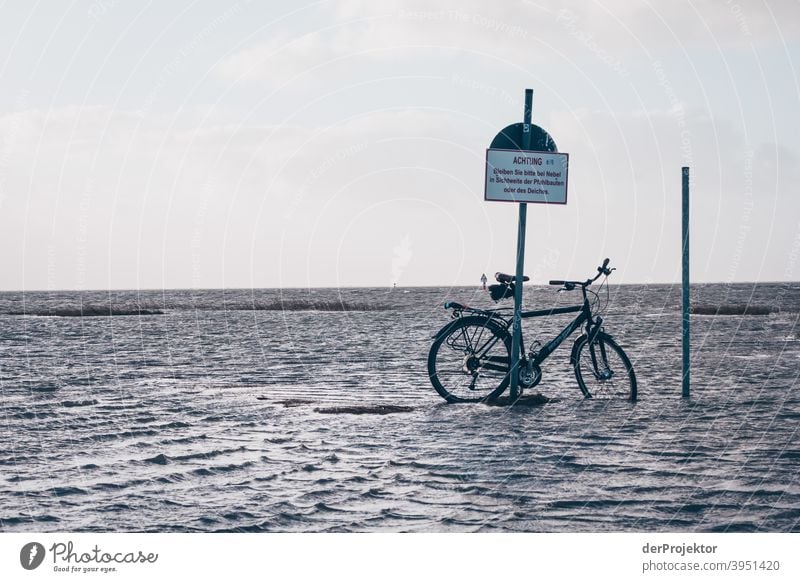 Schild mit Aufschrift: "Achtung" und Rad im Wasser in Sankt Peter-Ording Panorama (Aussicht) Totale Zentralperspektive Starke Tiefenschärfe Sonnenuntergang