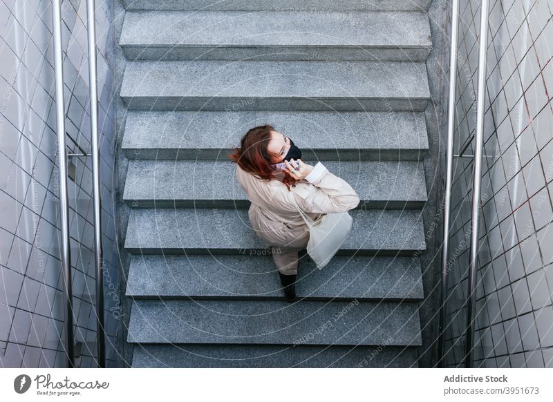 Frau in Maske mit Smartphone auf der Straße reden Großstadt Coronavirus Mundschutz neue Normale Treppe nach oben urban Bund 19 Ausbruch Seuche online verhindern