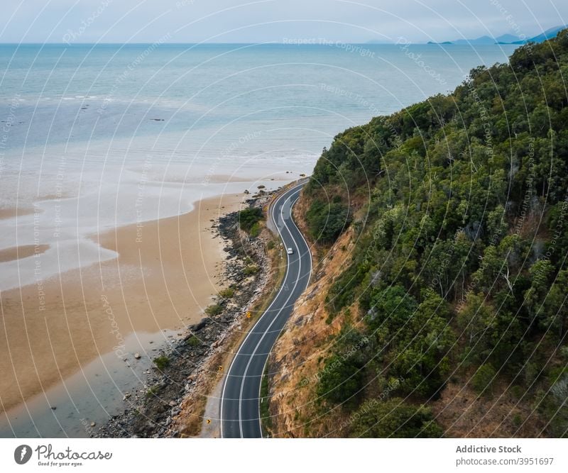 Autobahn in bergigem Gelände in der Nähe des malerischen Ozeans mit sandiger Küste Straße Meer Strand Hügel Baum Natur Landschaft Meereslandschaft PKW Reise