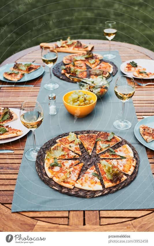 Abendessen in einem Hausgarten. Pizza, Salate, Früchte und Weißwein auf dem Tisch in einem Hinterhof Getränk Feier Speise trinken Essen Festessen Lebensmittel