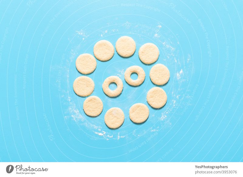 Herstellung von Donuts flachlegen. Ungekochter roher Teig für Donuts vorbereitet ausgerichtet Amerikaner backen Blauer Hintergrund Frühstück Kuchen Kalorien