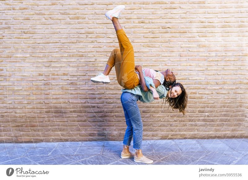 Komische multiethnische Frau, die ihren besten Freund huckepack trägt Huckepack tragen Spaß schwarz Afro-Look Mädchen Schüler zwei Menschen Lifestyle Lächeln