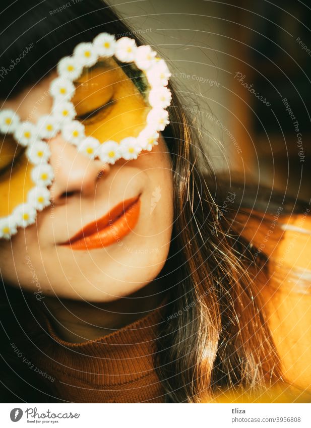 Frau mit Blümchen-Sonnenbrille im Sonnenlicht. Retrostimmung, Optimismus, gute Laune und Sommer. Sommerstimmung Frühling Sonnenschein farbenfroh gelb orange