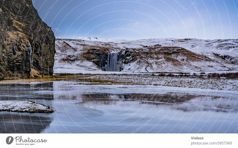 Wasserfall Skógafoss in Island Außenaufnahme Farbfoto natürlich Felsen Hügel Sturm Wind Wetter Wolken Himmel Landschaft Natur Schatten Licht Regen Schnee Frost