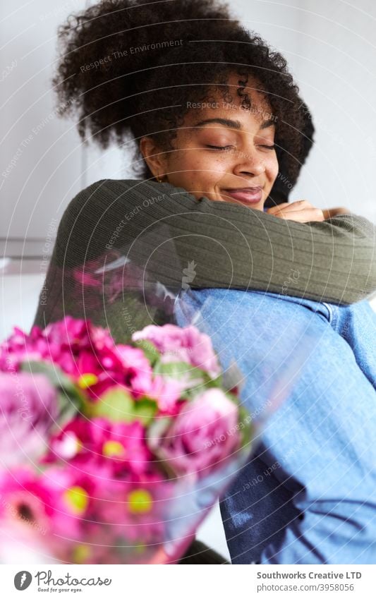 Romantisches Paar zu Hause mit Mann überraschend Frau mit Blumenstrauß feiern valentines Tag, Geburtstag oder Jahrestag und sie gibt ihm umarmen junges Paar