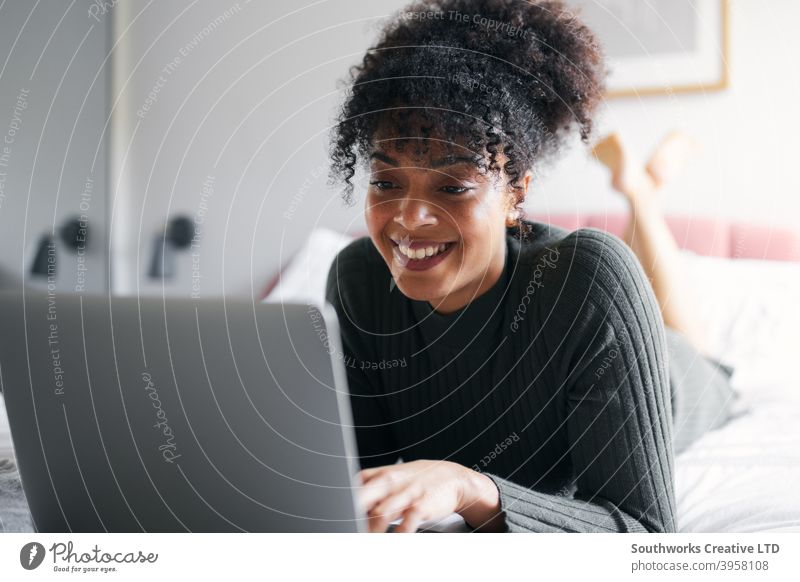 Frau liegend auf dem Bett arbeiten von zu Hause aus auf Laptop-Computer von zu Hause aus arbeiten Browsen WFH Sperrung covid-19 Coronavirus Schlafzimmer Lügen