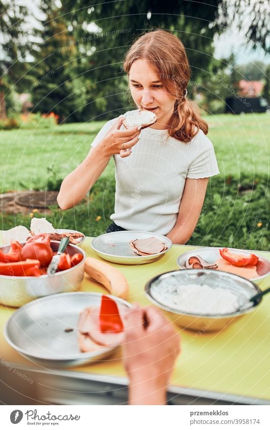 Familie beim Frühstück im Freien auf dem Campingplatz in den Sommerferien authentisch wirklich Banane gekochtes Fleisch langsames Leben Tischdecken im Freien