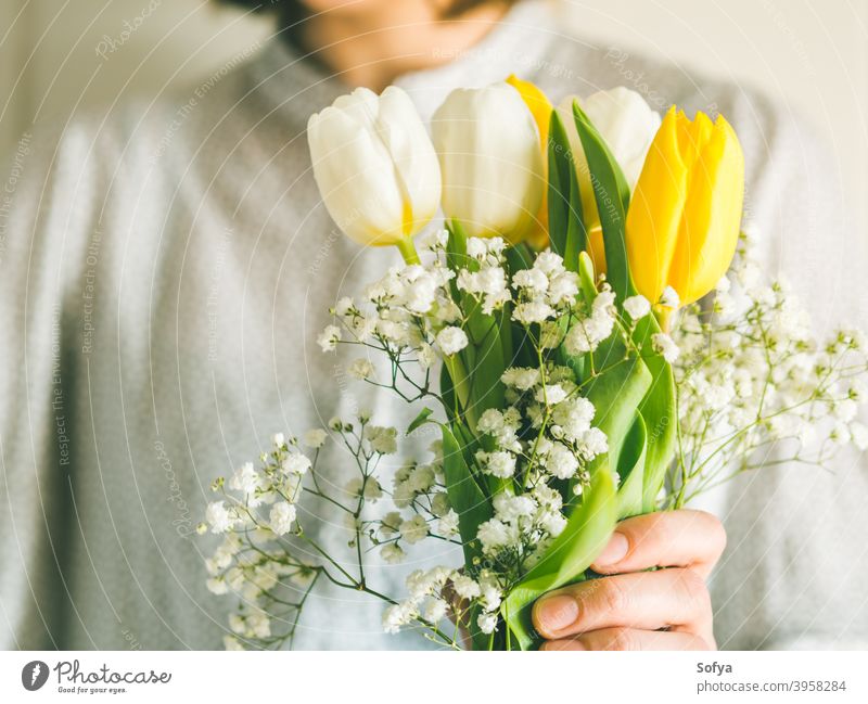 Frau hält Tulpenstrauß. Der Tag der Frau Blume Haufen Mutter geben Frühling Ostern Hände geblümt weiß gelb Dame März Geschenk Einladung Gruß Postkarte