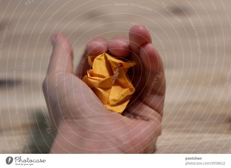 Eine Hand hält ein zerknüllte Stück Papier in orange. müll büro habd halten ideen kreativität schreibblockade Zettel lernen Inspiration Idee Wut ärger