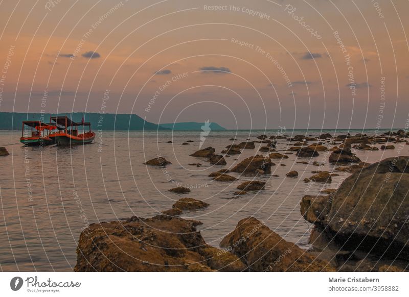 Blick auf zwei Khmer-Fischerboote beim Anlegen an der felsigen Küste der Insel Koh Rong in Kambodscha bei Sonnenuntergang khmer fischerboot Insel Koh rong