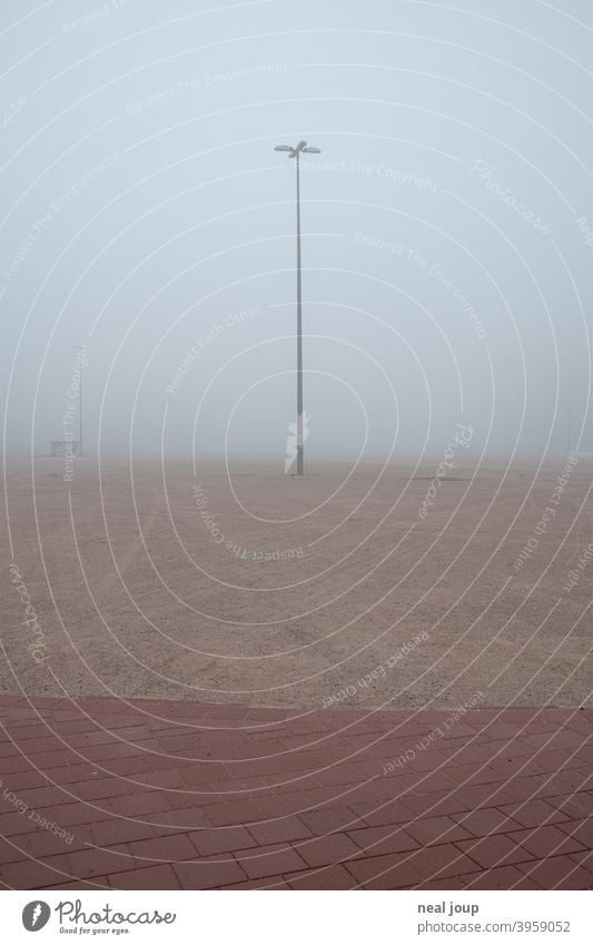 Straßenlampe auf einer im Nebel verschwindenden Brachfläche; ein Parkplatz Außenaufnahme Stadt urban Brache Brachland Industrie Fläche morgen diffus Horizont