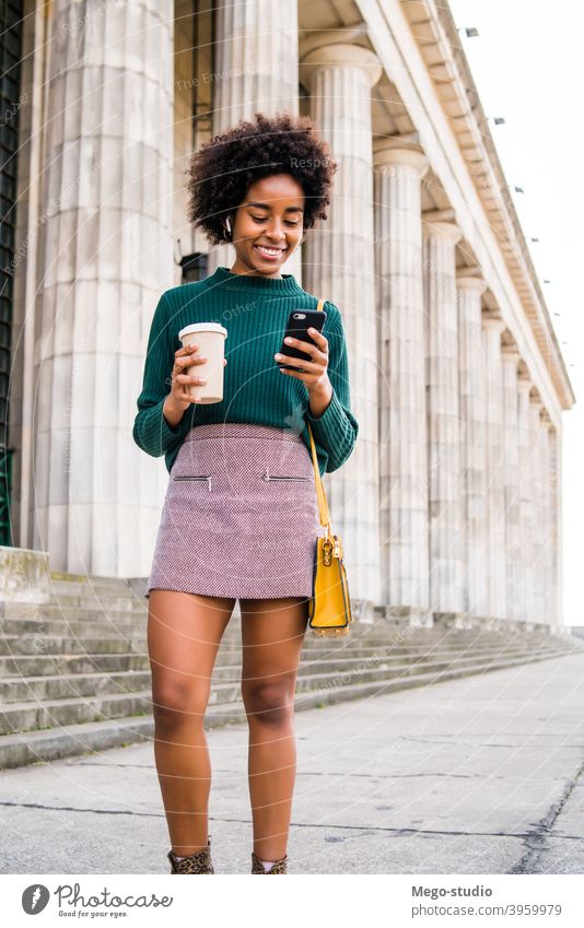 Geschäftsfrau, die ihr Mobiltelefon im Freien benutzt. Afro-Look Business Frau Mobile Telefon schwarz modern Stil brünett Apparatur positiv Konzept Anschluss