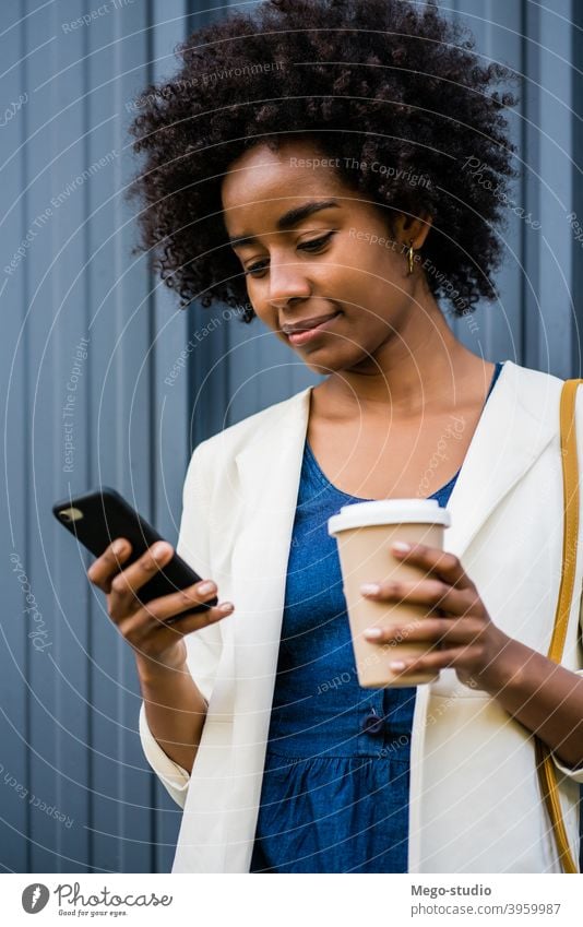 Geschäftsfrau, die ihr Mobiltelefon im Freien benutzt. Afro-Look Business Frau Mobile Telefon schwarz modern Stil brünett Apparatur positiv Konzept Anschluss