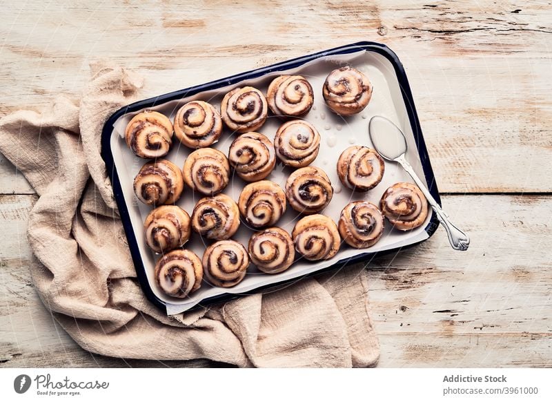 Leckere Zimtschnecken auf Tablett auf Tisch Brötchen rollen gebacken Bäckerei Glasur Zuckerguss Dessert lecker Lebensmittel süß Feinschmecker Gebäck hölzern