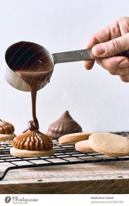 Kropfenkoch mit Schokoladenüberzug auf Keksen Belag eingießen Koch vorbereiten süß Dessert Karamell hinzufügen Sahne Tisch Gebäck kulinarisch lecker