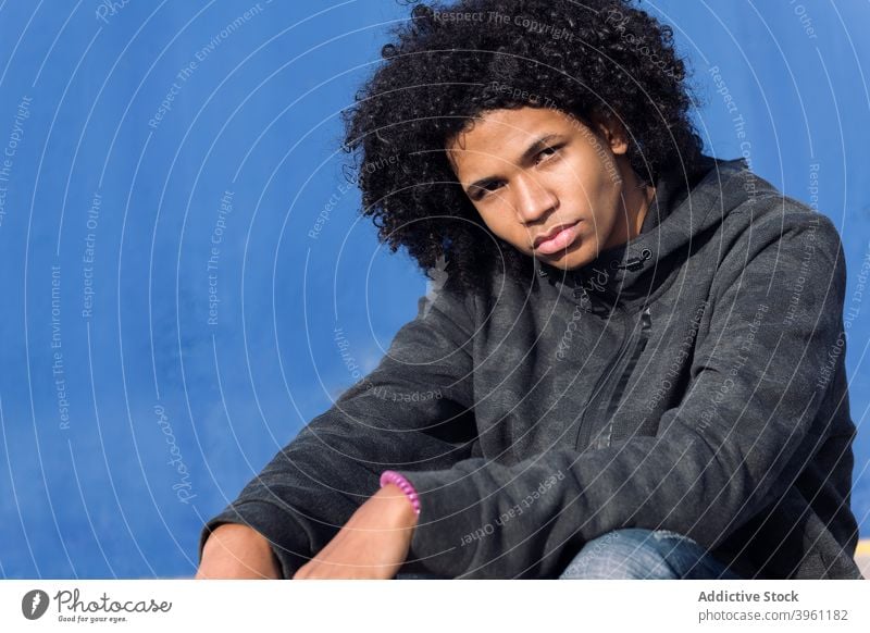 Pensive Hipster teen Kerl in der Nähe von blauen Wand Mann Teenager nachdenklich ernst besinnlich krause Haare Afro-Look informell tausendjährig männlich