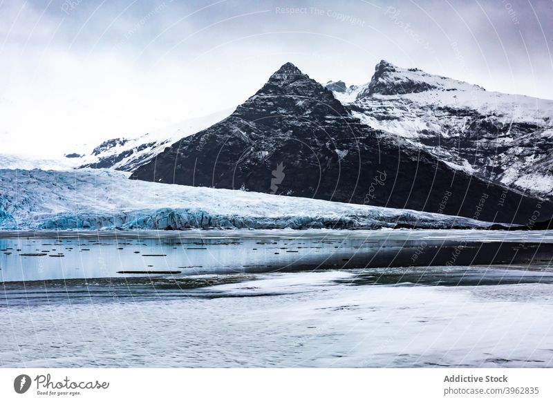 Bergsee im Winter unter grauem Himmel Berge u. Gebirge See Hochland Landschaft Teich Schnee Wasser Windstille Island wolkig malerisch Natur felsig kalt Kamm