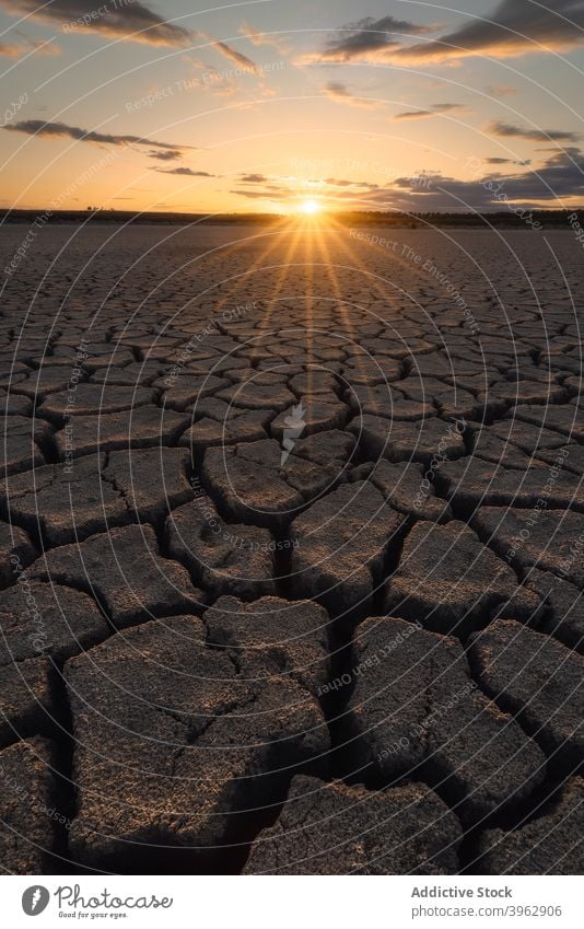 Trockenes rissiges Gelände unter bewölktem Sonnenuntergangshimmel Dürre trocknen Boden Natur wüst Umwelt Land Riss heiß Ökologie flau Himmel wolkig Hintergrund